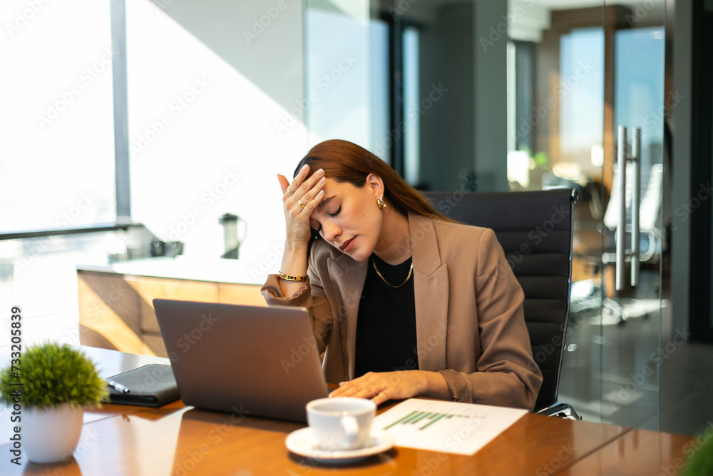 Stressed woman closing her eyes and sitting in a meeting room