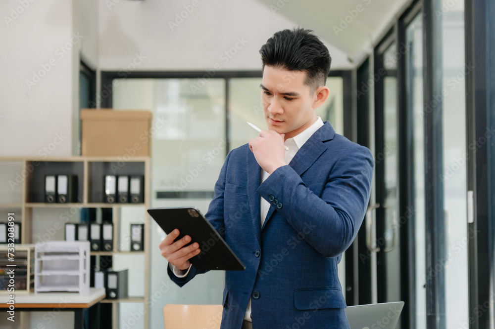 Young attractive Asian male office worker business suits smiling at camera in office Young attractive Asian male office worker business suits smiling at camera in office