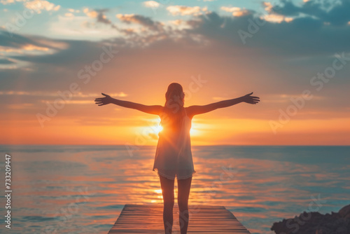 Woman with open arms under the sunrise at seaside wellness concept. © Hunman