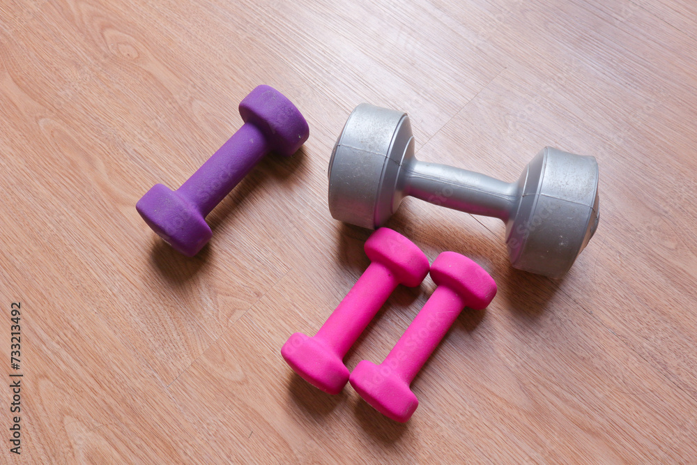 dumbbells with plastic coating on a wooden background dumbbells with plastic coating on a wooden background