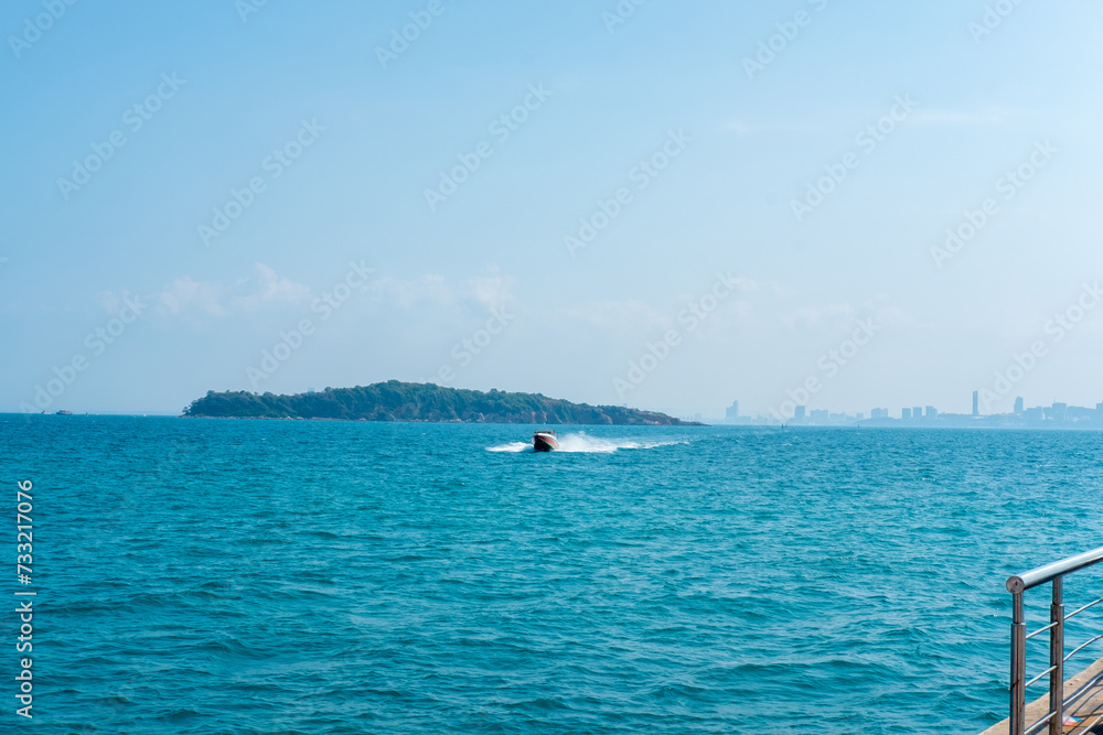 Seascape with speed boats coming to the pier, back view of Pattaya city, Thailand