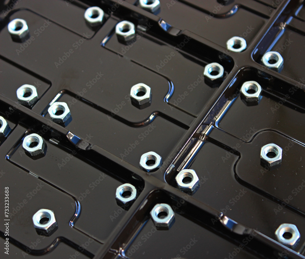 Steel nuts on a glossy plastic panel with rectangular compartments
Steel nuts on a glossy plastic panel with rectangular compartments