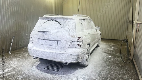 Black car being covered in foam on the self-service car wash. Back and side view. High quality photo
