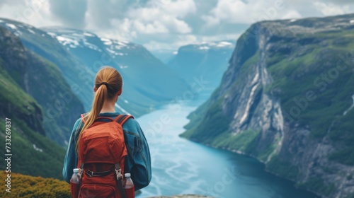 A young woman stands with her back and admires the view of snowy mountains and lake. A traveler traveling on vacation in the most beautiful place in the world. Winter vacation