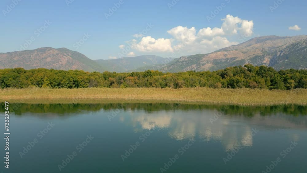 A serene natural landscape with a lake reflecting the sky, surrounded by misty mountains in the background. A serene natural landscape with a lake reflecting the sky, surrounded by misty mountains in the background.