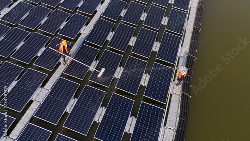 Professional workers cleaning and inspecting solar panels on a floating buoy. Power plant with water, renewable energy sources, Eco technology for industrial electrical energy.
