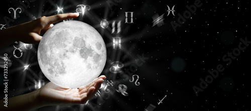 Astrological zodiac signs over the moon in hand. Knowledge of the stars in the sky. The power of the universe concept.