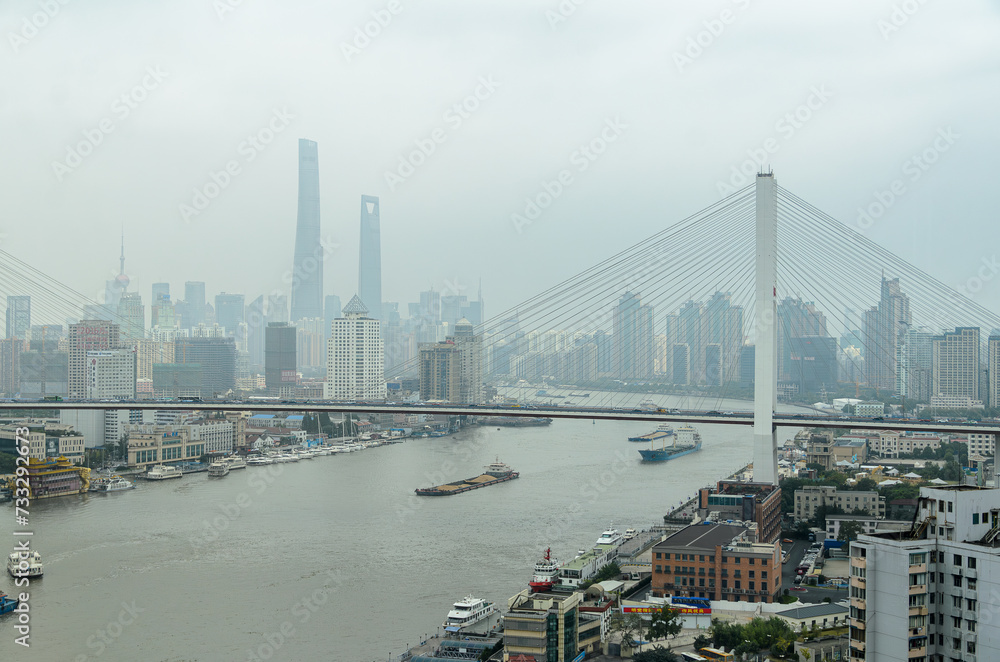 View of Huangpu River ship traffic somewhat shrouded by air pollution in Shanghai China