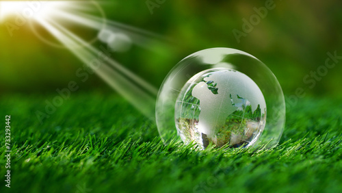 Glass earth globe crystal inside of bubble on green grass in the garden background with sunshine.Safe world, saving the planet concept, ecological friendly and World Environment Day.Reforestation.