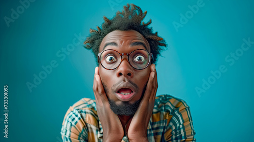 Shocked man surprised with hands up and open mouth on blue background. photo