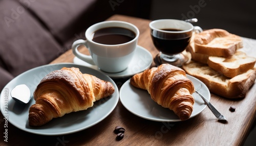 A table with two plates of croissants and two cups of coffee