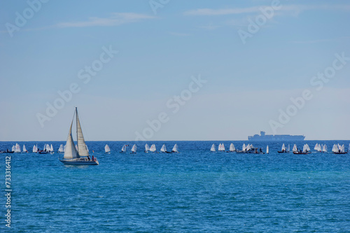 boats in the Mediterranean with a bottom container transporter and small boats and a sailboat