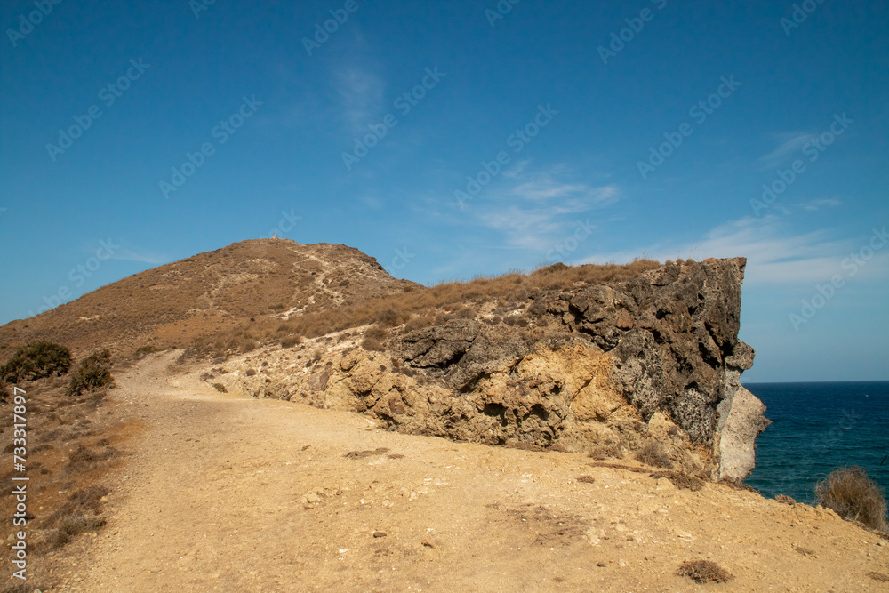 Sendero de subida al punto geodésico sobre la colina conocida como Cerro de Los Genoveses, en San José, Almería, España. Vista del paisaje costero y desértico a orillas del mar Mediterráneo.