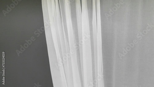 Waves of the white tulle curtain are falling in motion. The fabric is delicate and thin airy for the window. photo