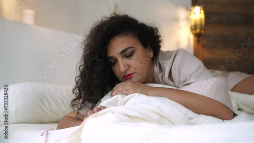 A middle-aged woman is sad in her bedroom, lying on the bed, feeling of loneliness and unhappiness in the bedroom at home. The concept of trouble and despair in your personal life 4K