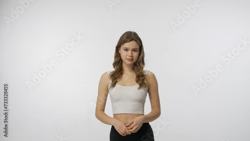 Portrait of young blonde European girl on white background of studio. Girl in sports uniform poses and looks at the camera. © kinomaster