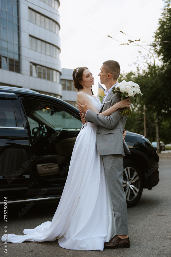 bride and groom with a black car