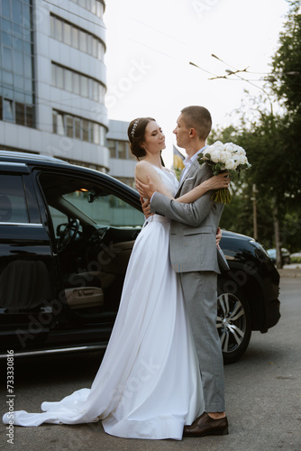 bride and groom with a black car