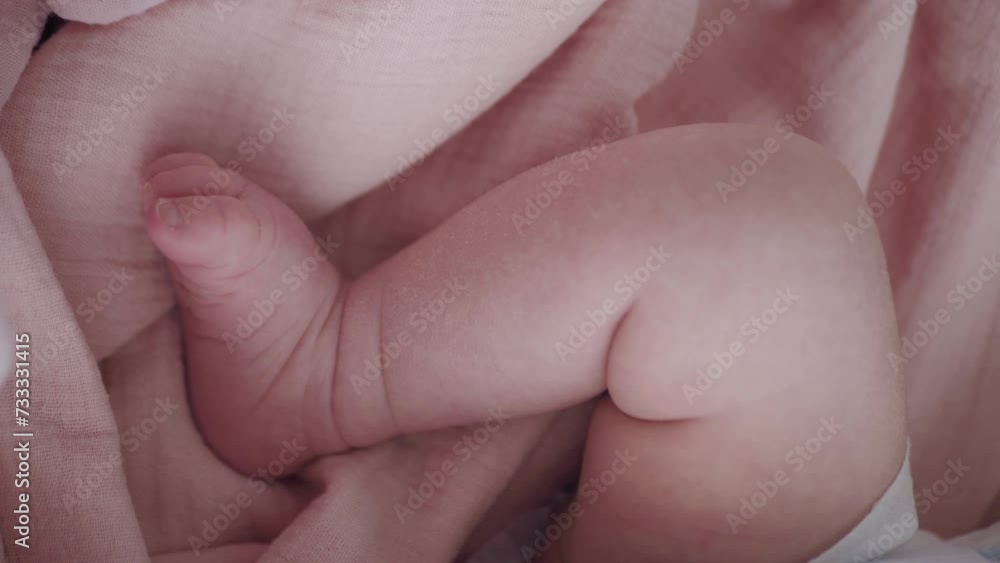 Portrait of a beautiful newborn baby girl lying in a white cot under a pink plaid with ruffles at home with a bow on her head and looking around. Portrait of a beautiful newborn baby girl lying in a white cot under a pink plaid with ruffles at home with a bow on her head and looking around.