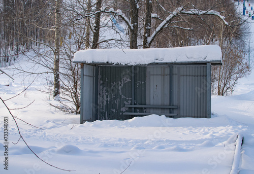 Abandoned snow-covered bus stop in a forest area on a winter day