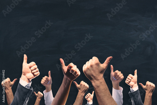 Various male and female hands showing thumbs up on chalkboard wall background with mock up place.