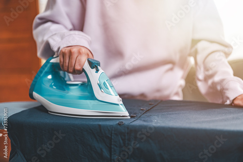 clothes, appliance, home, housework, iron, ironing, laundry, steam, clean, domestic. close-up young woman's hand using electric steam, water vapor from iron press pile shirt clothes on an ironing.