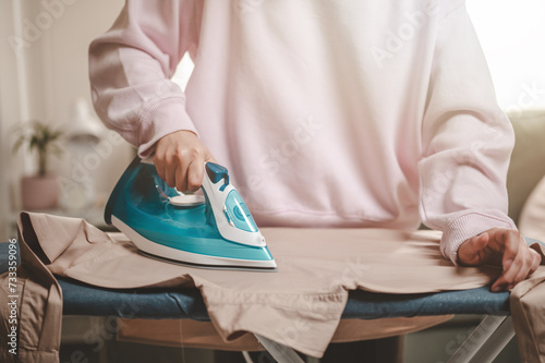 clothes, appliance, home, housework, iron, ironing, laundry, steam, clean, domestic. close-up young woman's hand using electric steam, water vapor from iron press pile shirt clothes on an ironing.