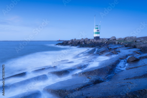 A lighthouse on the beach during blue hour. A landmark in maritime navigation. Long exposure. Natural composition. Photo for wallpaper and background.