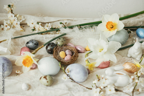 Happy Easter  Stylish easter eggs  bunnies  cherry blossom and daffodils on rustic table. Modern natural dyed eggs and spring flowers. Easter still life decor in countryside home