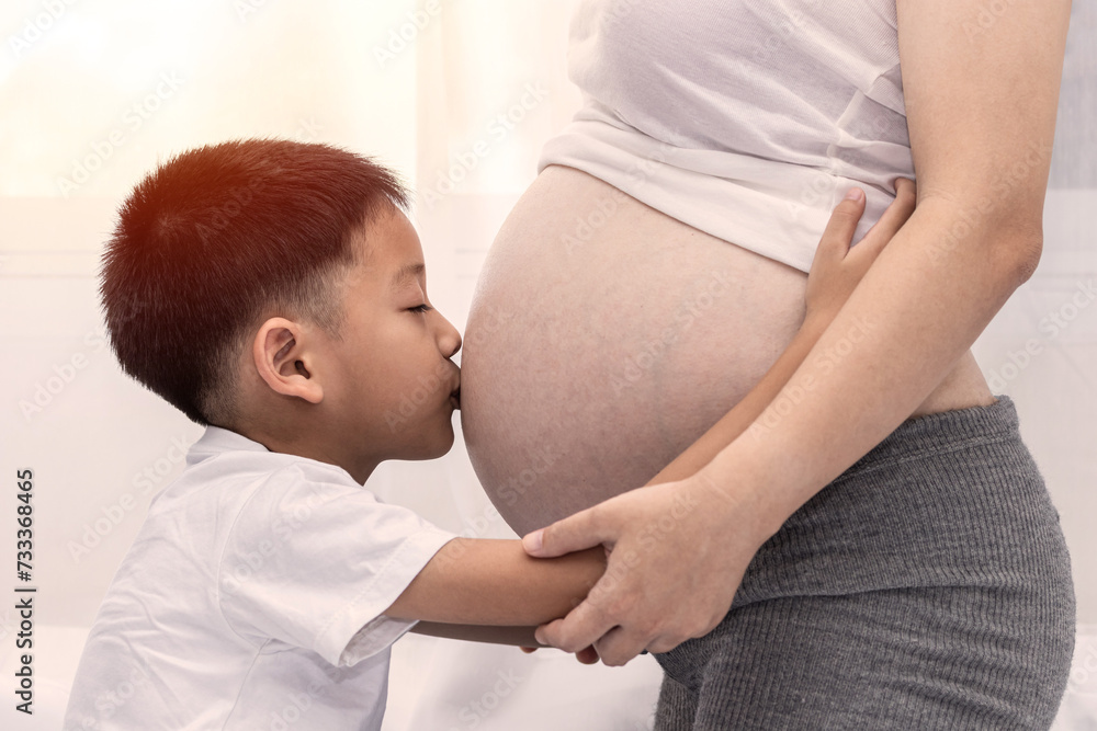 Little boy Kissing the belly of the pregnant mother. Pregnant mother and son are happy. little child boy looking at her mother's pregnant tummy Little boy Kissing the belly of the pregnant mother. Pregnant mother and son are happy. little child boy looking at her mother's pregnant tummy