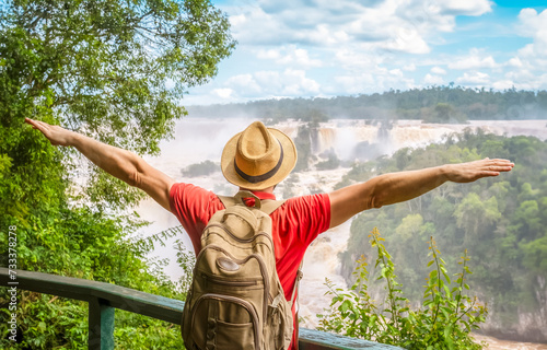 Iguazu Waterfalls, Brazil - Traveler man with raised arms watching Iguacu Falls in Brasil and Argentina photo