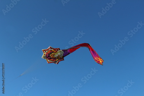 Aquilone raffigurante una donna bionda con i capelli raccolti, disegnata in stile liberty che vola nel cielo blu. La coda dell’aquilone rappresenta un lungo vestito elegante photo