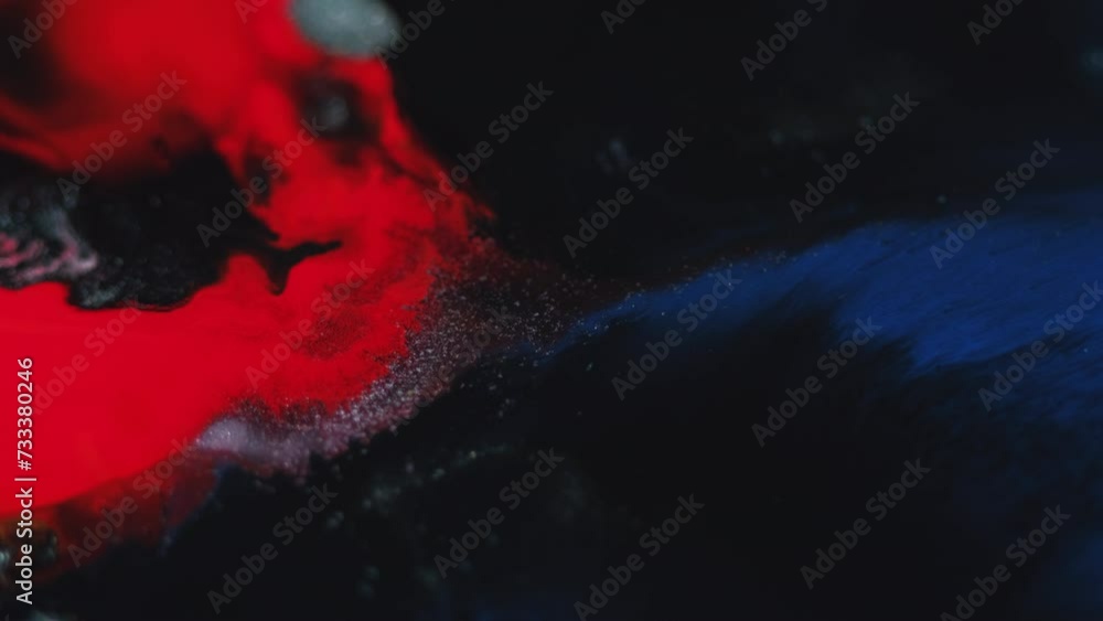 Paint splash. Ink wave. Color mist. Defocused red blue black particles texture fluid drop mix flow motion dark abstract background.