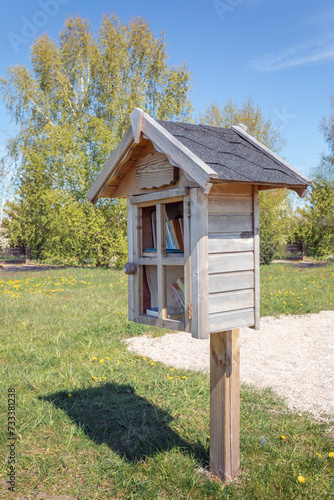 Small wooden, homemade house in the city park using for a library where citizens can take or leave books for free. Second life of the books.