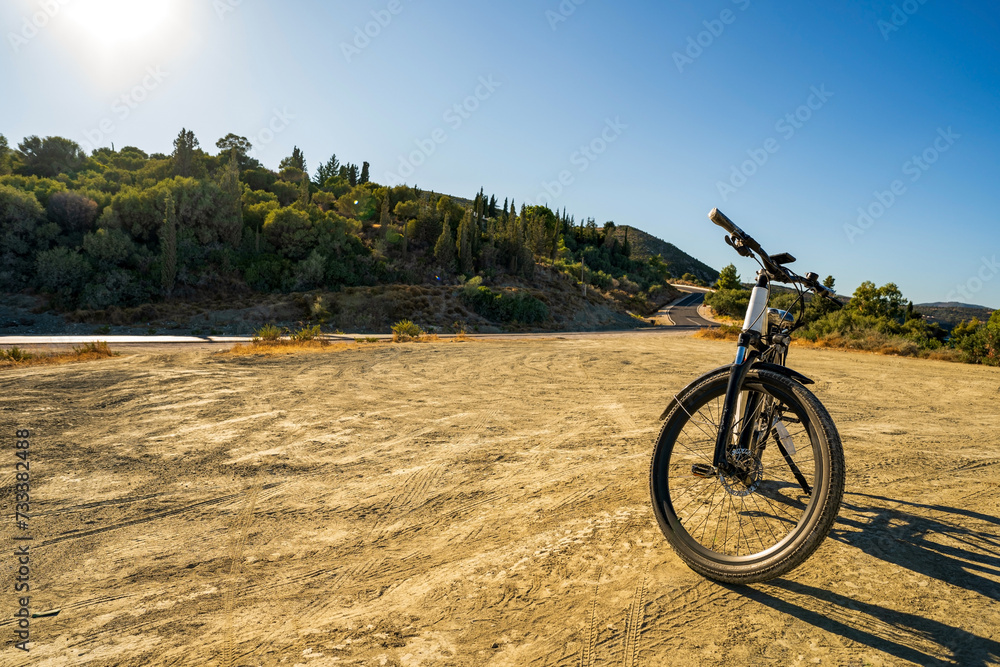Wide angle shot of an electric bicycle parked on a dirt against highway in Greece, Europe