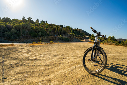 Wide angle shot of an electric bicycle parked on a dirt against highway in Greece, Europe