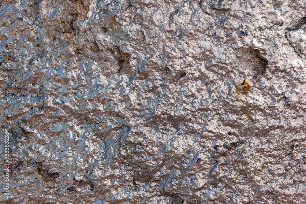 The rough concrete wall is painted with rose gold glitter paint The rough concrete wall is painted with rose gold glitter paint
