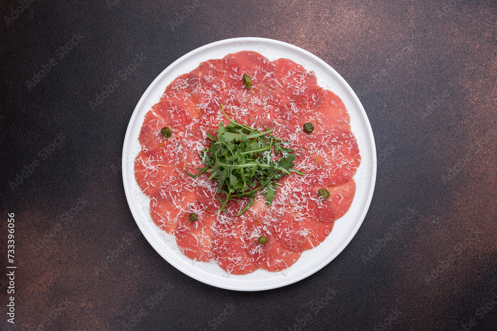 Fresh carpaccio with veal and arugula on a round plate Fresh carpaccio with veal and arugula on a round plate