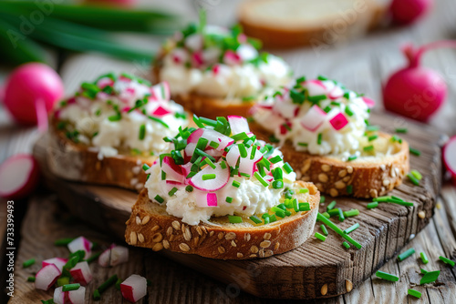 bruschetta with grain bread, soft cheese, radish and chives on wooden background