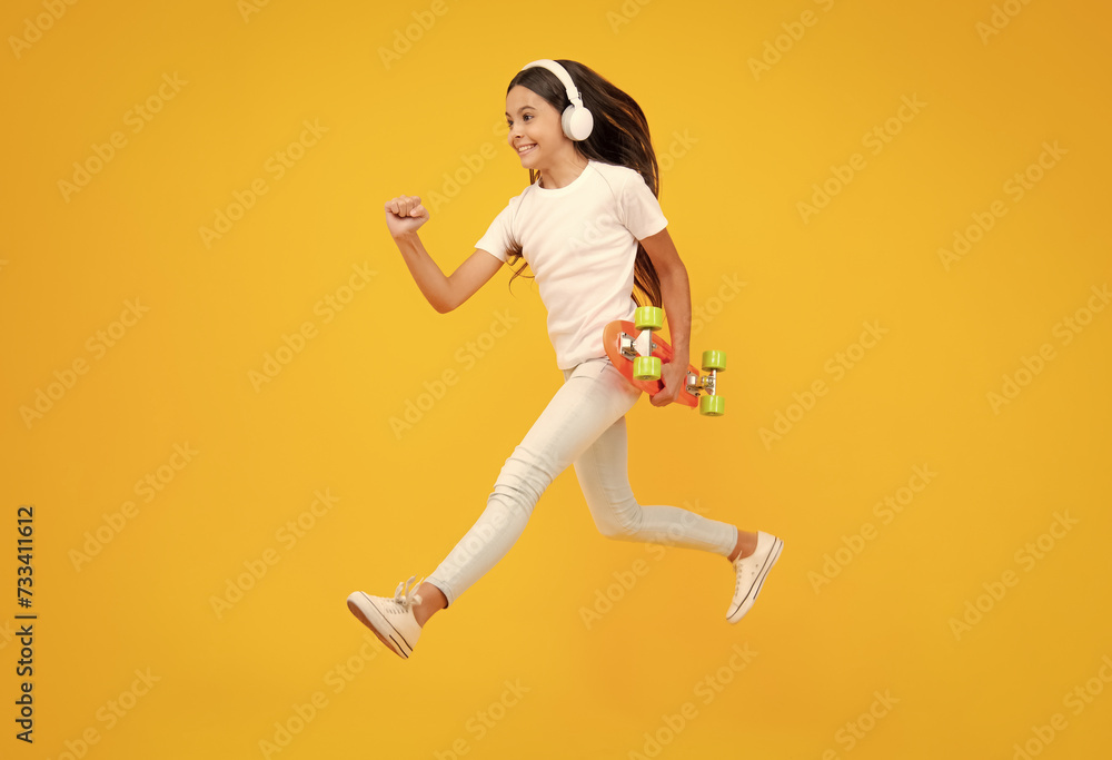 Teen girl 12, 13, 14 years old with skateboard over studio background. Jump and run. Cool modern teenager in stylish clothes. Teenagers lifestyle, casual youth culture. Excited teenager emotions.