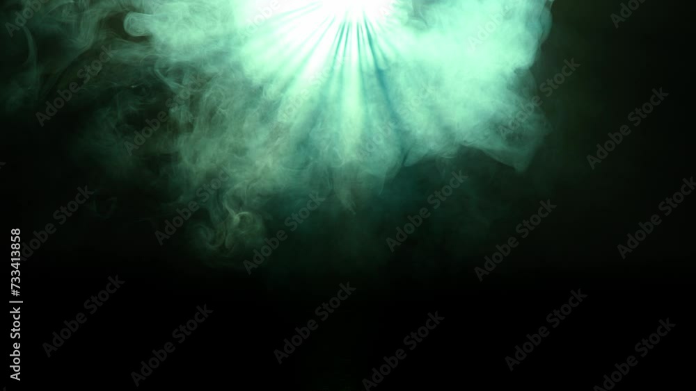 Studio shot of projector haze isolated on black background. Green light rays shining from above with smoke moving around.