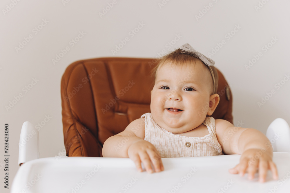 Happy little baby girl sitting in high chair in kitchen at home Happy little baby girl sitting in high chair in kitchen at home