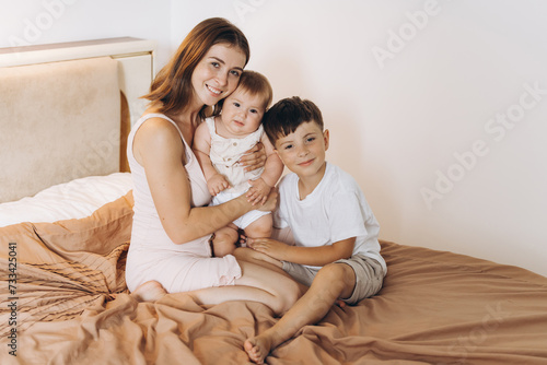 Happy young mother spending time with her children in the bedroom