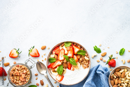 Yogurt with granola and strawberries on white background. Healthy snack or breakfast. Top view with copy space.