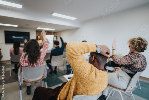 Engaged adults participating in an educational workshop  actively raising hands to ask questions in a well-lit modern classroom.