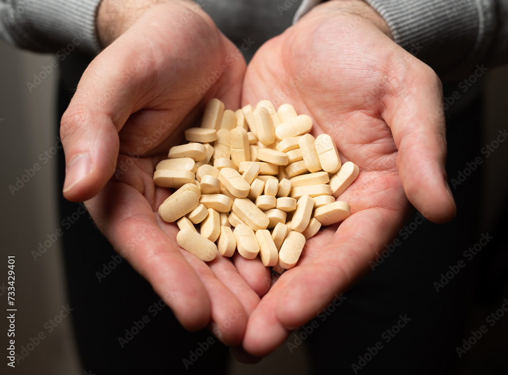 Male hands hold handful of white medicine tabs pills, concept of wellness Male hands hold handful of white medicine tabs pills, concept of wellness
