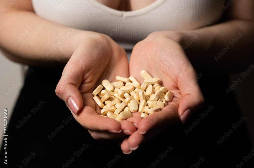 Obraz premium Female breast health awareness concept: woman hands hold handful of supplements for breast support and cancer prevention