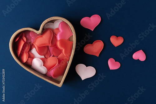 Fabric decorative hearts in heart-shaped box on dark-blue background. Valentine’s day greeting concept