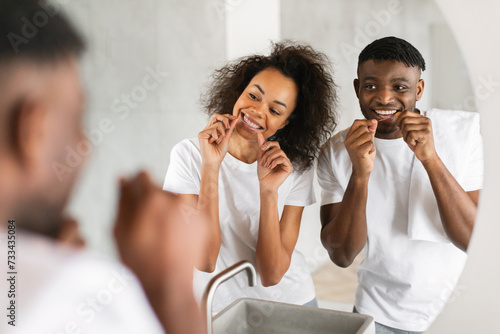 African couple uses dental floss practices oral care in bathroom photo