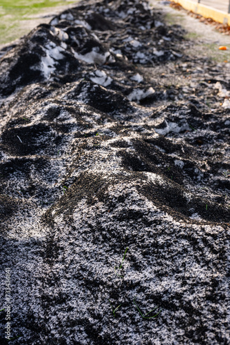 Artificial turf infill mixed with snow and ice by a football field.